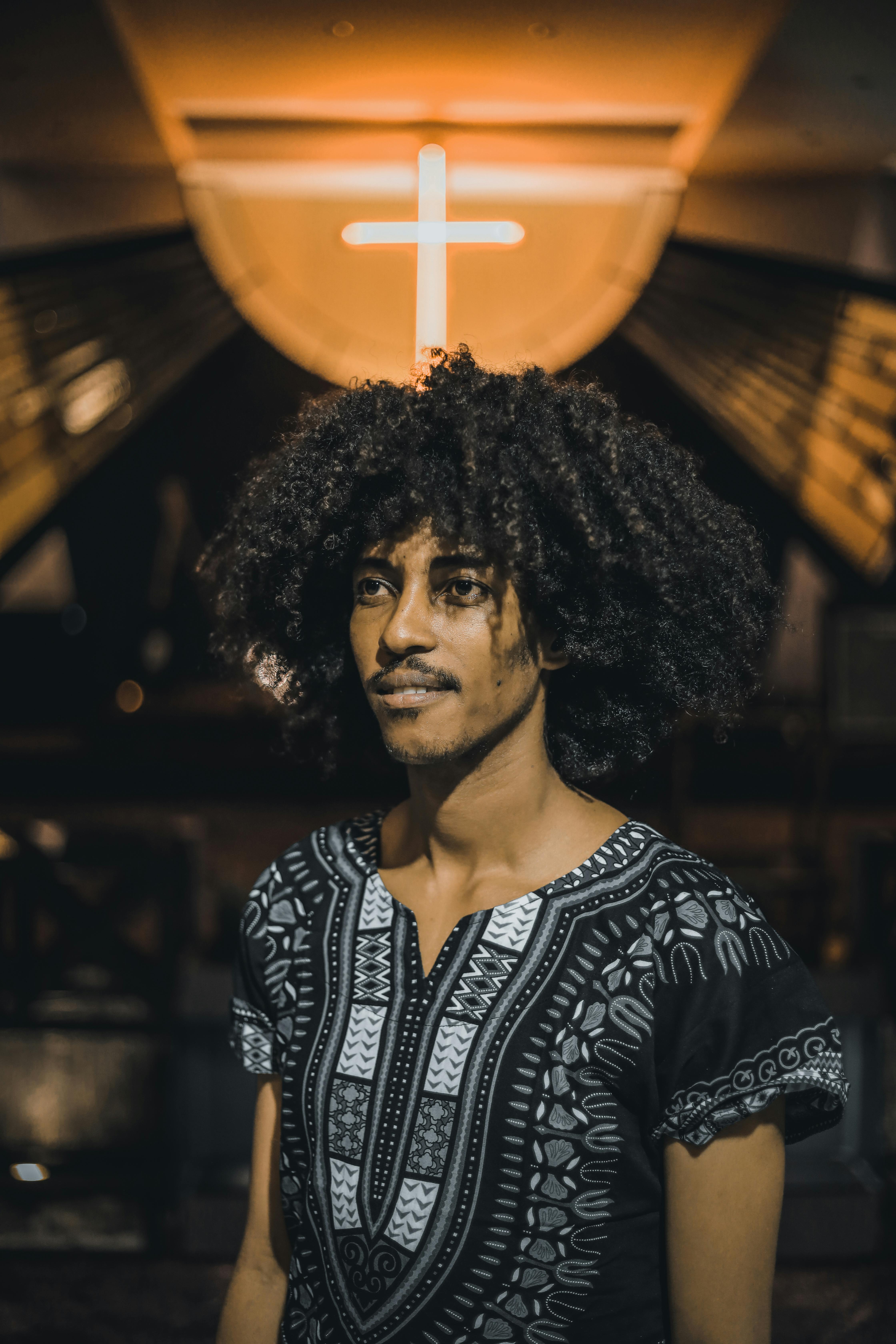 Young black man with curly hair against neon cross · Free Stock Photo