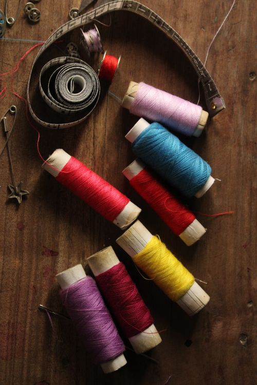 Free Vibrant spools of thread and sewing tools on a rustic wooden surface. Stock Photo