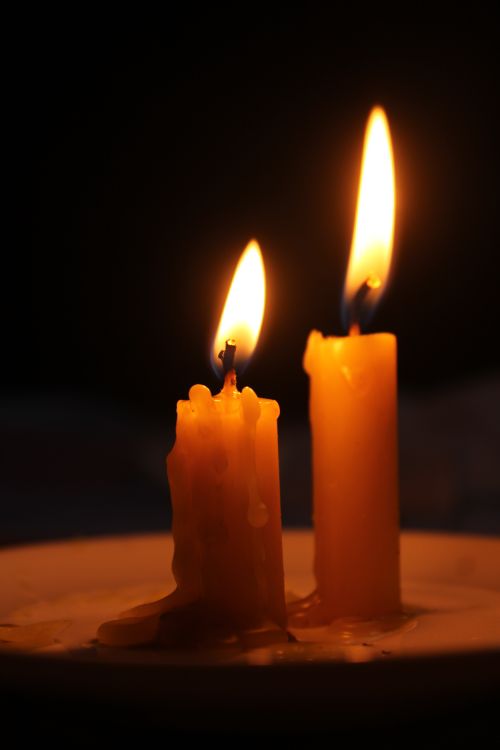 Free Two candles burning warmly in the dark, creating a peaceful and cozy ambiance. Stock Photo