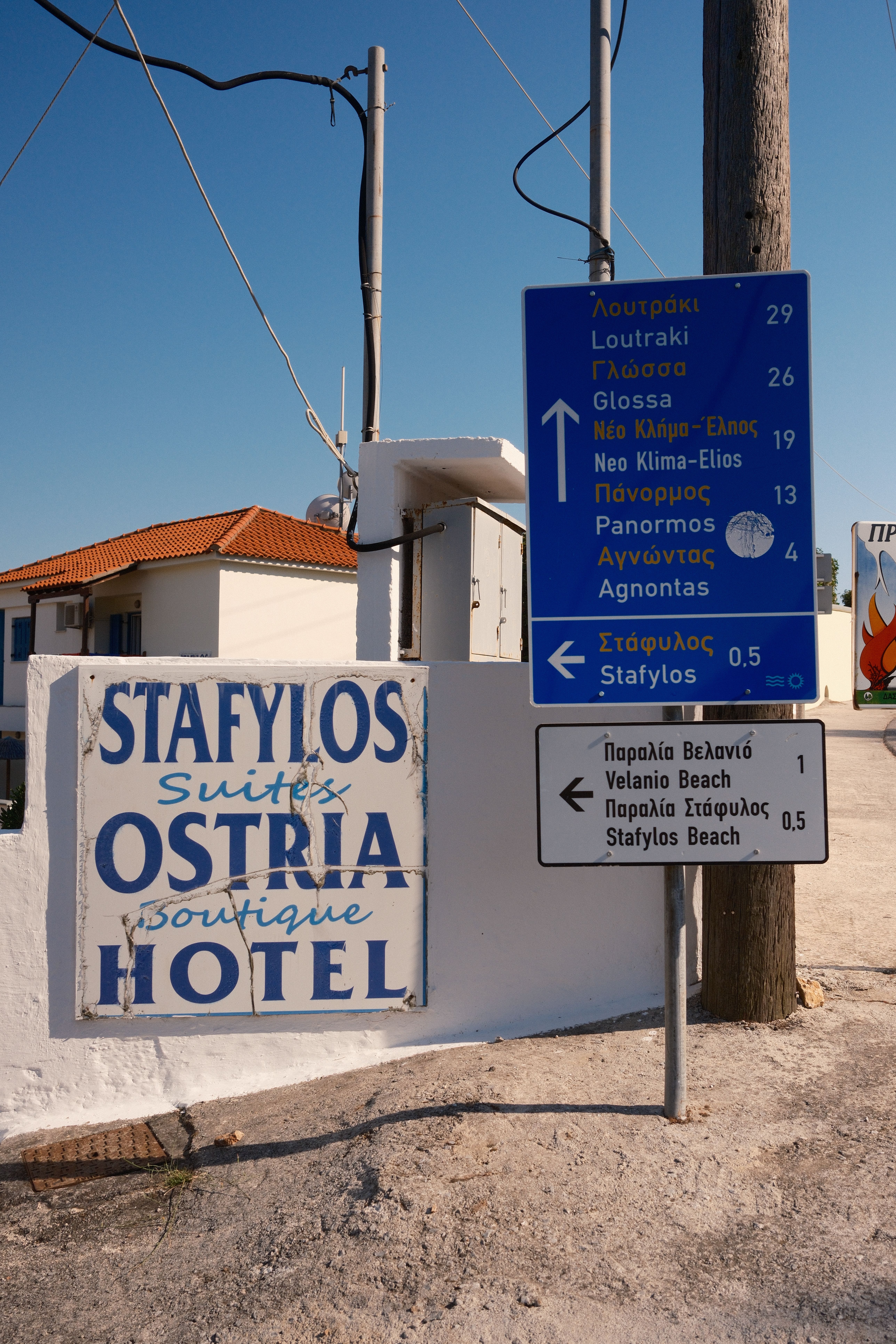 Directional signs and hotel signage near Stafylos Beach, showcasing local attractions in Skopelos, Greece.