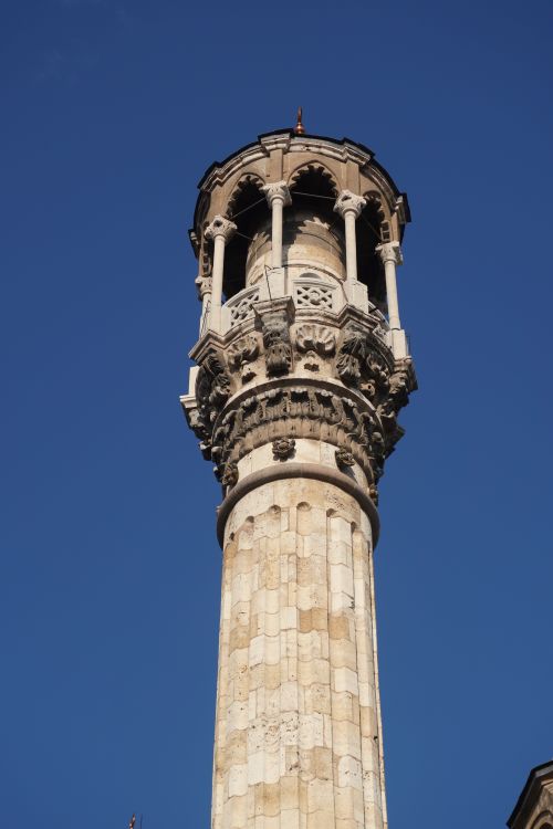 Free An ornate stone minaret set against a clear, bright blue sky, showcasing architectural beauty. Stock Photo