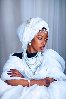 Portrait of an elegant African woman wearing white traditional attire and jewelry.
