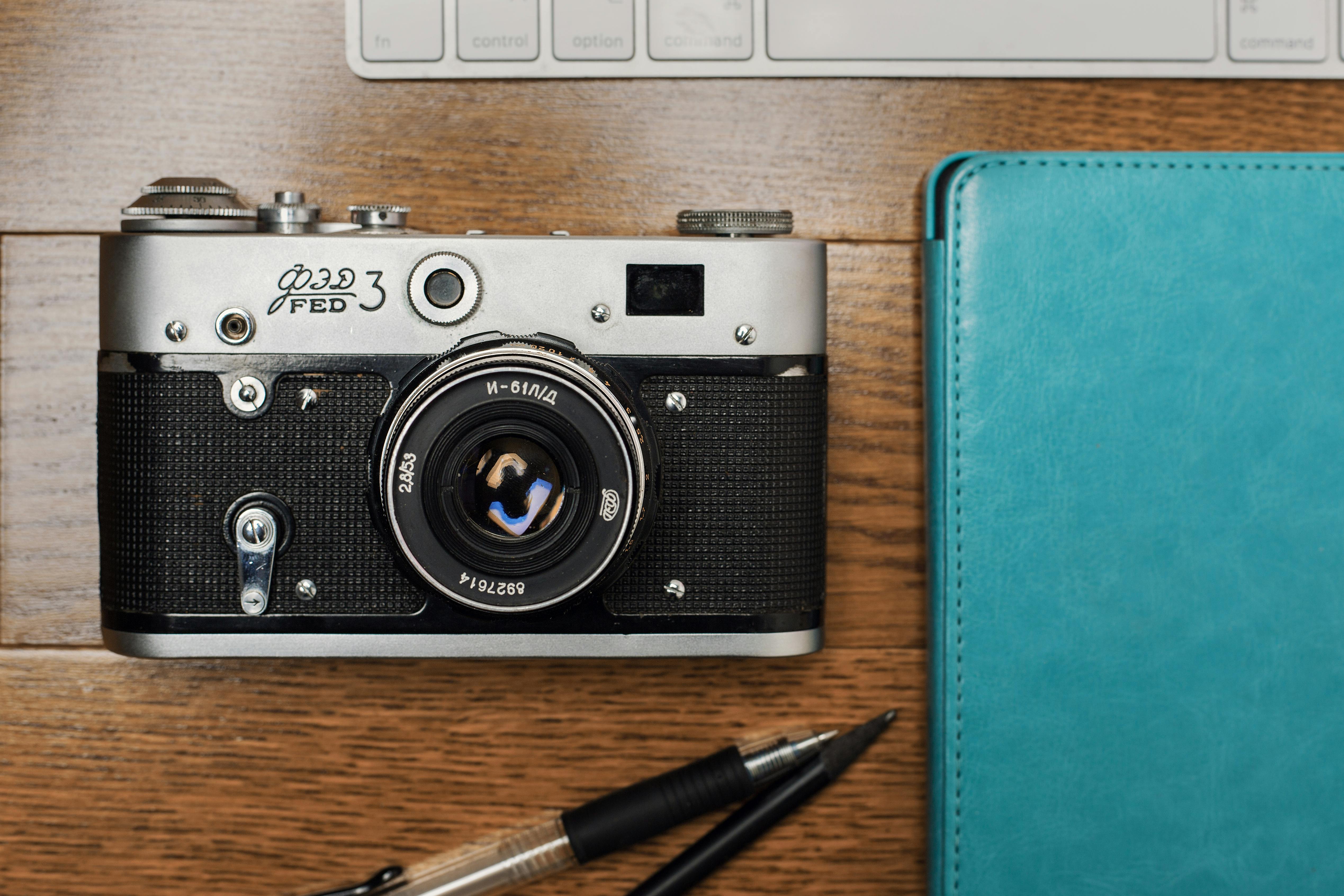 black and silver camera beside blue leather case