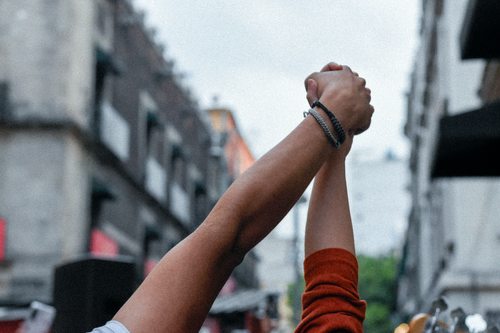 Free Two people holding hands in a triumphant gesture in Mexico City's vibrant streets. Stock Photo