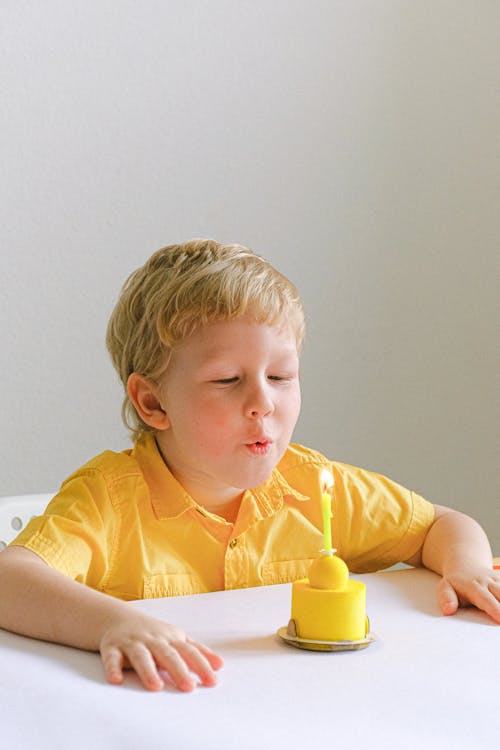 Free Boy In Yellow Polo Blowing A Candle Stock Photo