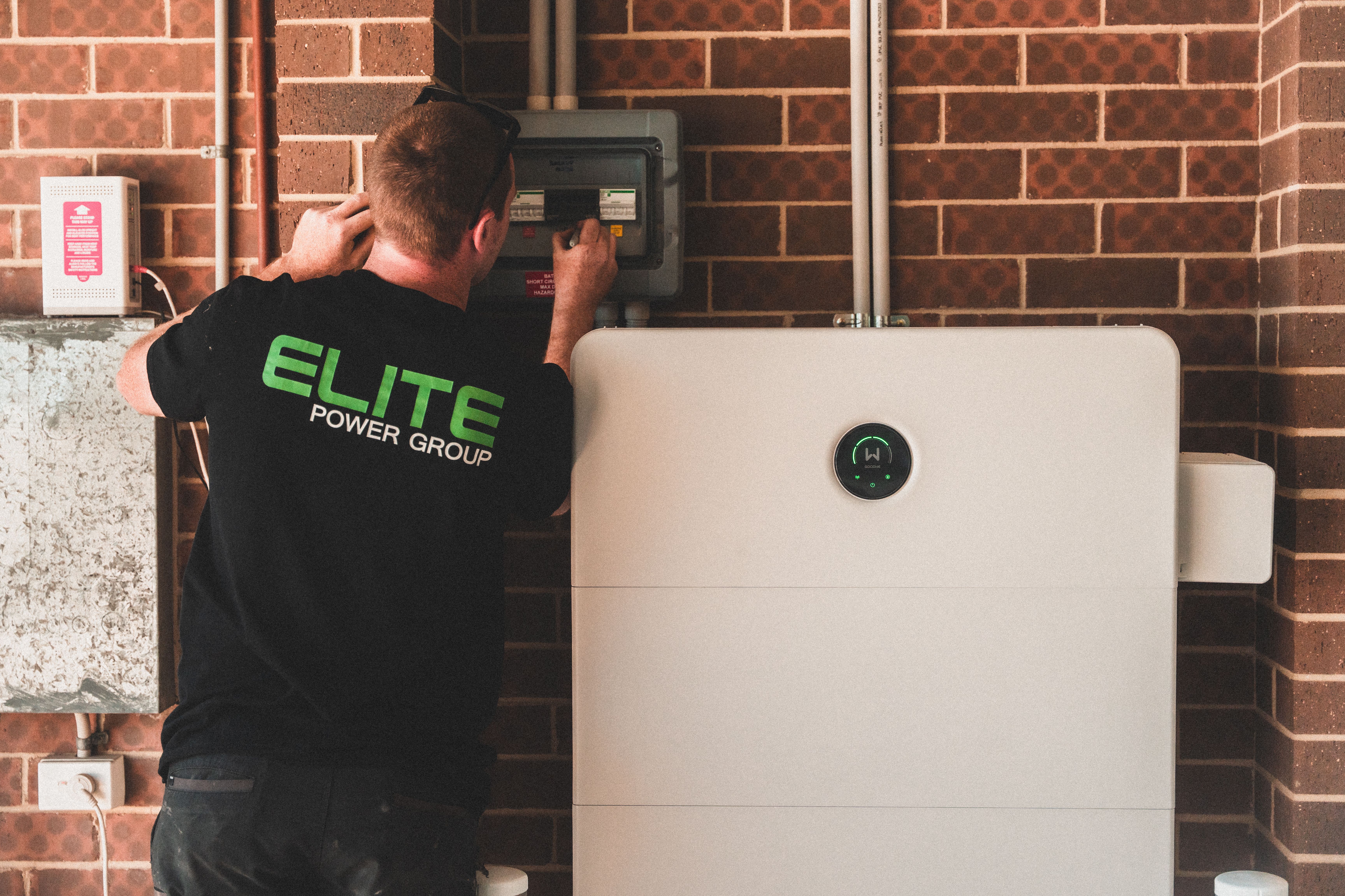 Electrician installing a home energy battery storage unit. Renewable and sustainable energy solution for residential use.
