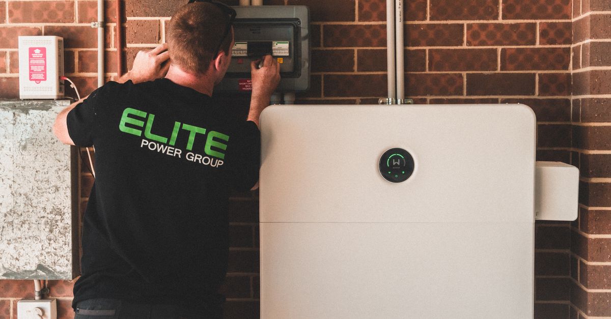 Electrician installing a home energy battery storage unit. Renewable and sustainable energy solution for residential use.