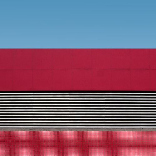 Free A minimalist architectural photo featuring red and white patterns against a clear blue sky. Stock Photo