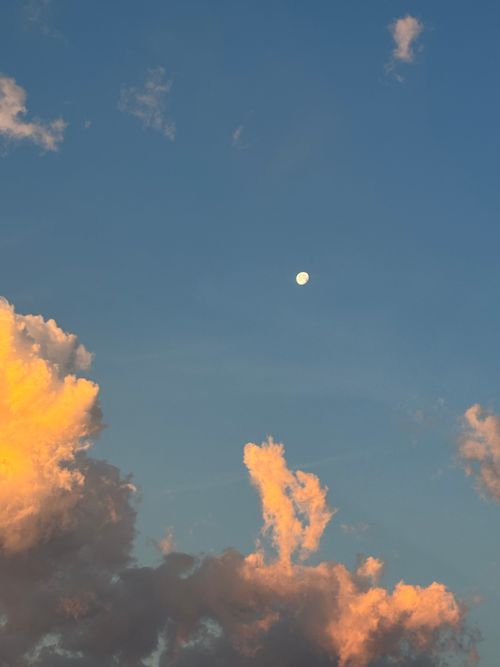 Free A tranquil sky view with the moon surrounded by colorful evening clouds, capturing a peaceful moment. Stock Photo