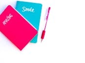 白色背景上有一间彩色公寓，旁边放着碧绿色和粉色的笔记本以及配套的笔