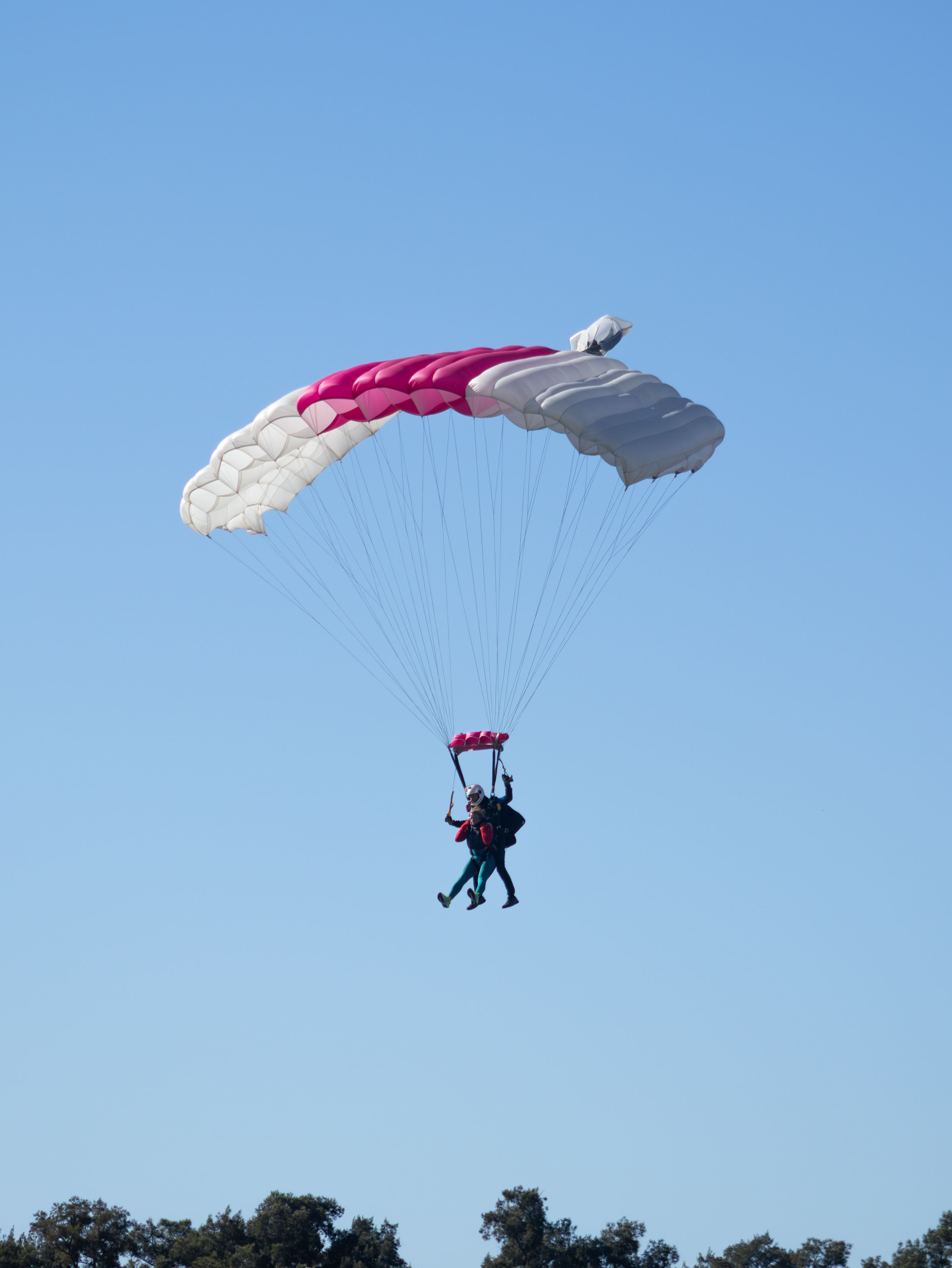 Tandem skydivers floating gracefully with a parachute over Buenos Aires.