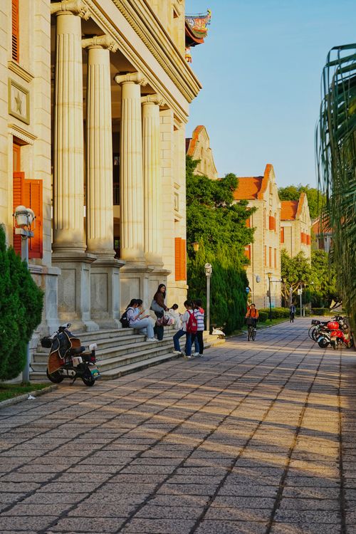 Free A serene university campus scene featuring classical architectural elements and students relaxing outdoors. Stock Photo