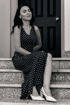 Elegant woman in a polka dot dress sitting on stairs in Baku.