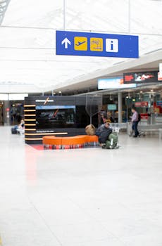 High-angle view of a modern airport terminal with travelers and visible signage.