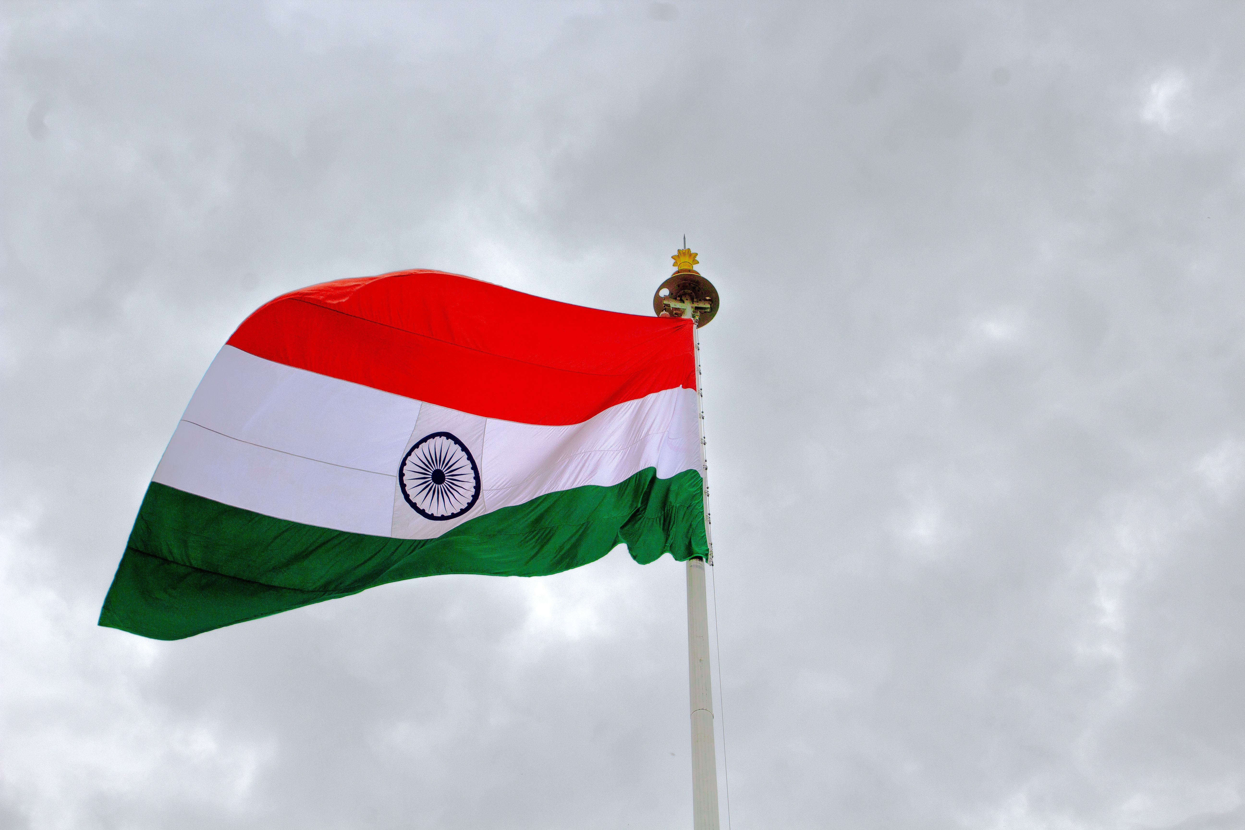 High-angle view of the Indian flag waving against a grey cloudy sky, symbolizing pride and unity.