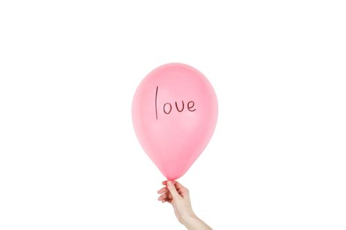 Free A hand holding a pink balloon with 'love' written on it, against a white background. Stock Photo