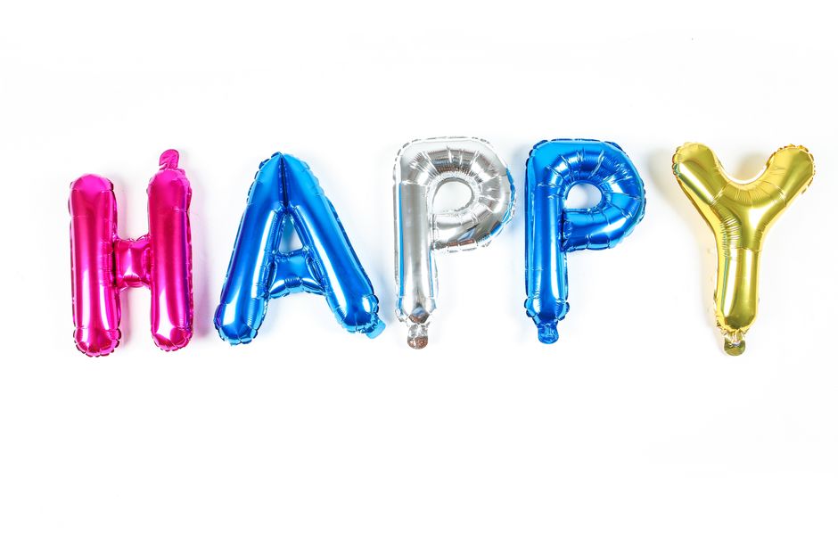 Fotomural Globos metálicos brillantes y coloridos que deletrean la palabra 'Feliz' sobre un fondo blanco.