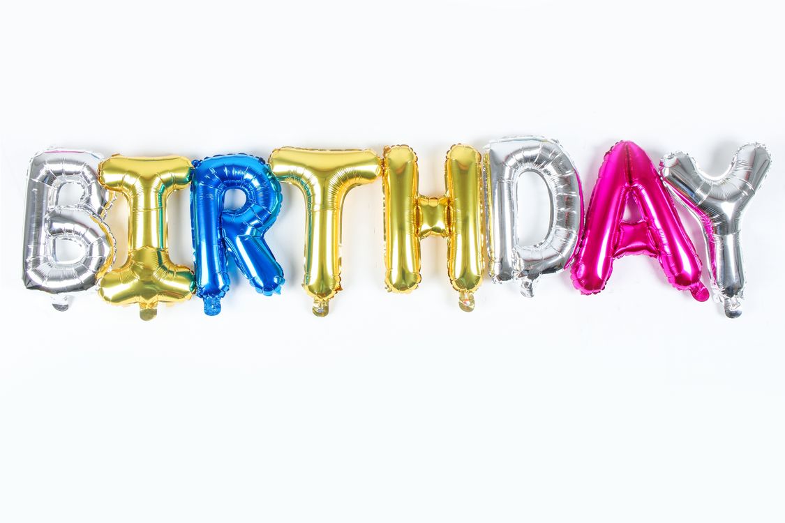Colorful metallic balloons spelling BIRTHDAY against a festive wall display with streamers