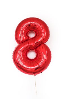 Vibrant red foil balloon shaped like the number eight against a white background.