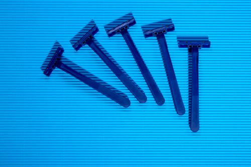 Free A set of five blue disposable razors arranged on a textured blue surface. Modern and minimalist design. Stock Photo