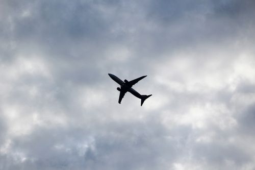 Free Silhouette of an airplane flying through a cloudy sky, capturing a serene and powerful aviation moment. Stock Photo