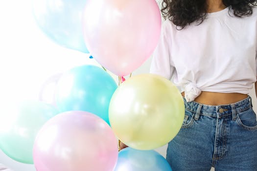 A vibrant collection of pastel balloons held by a person in a casual outfit, perfect for a festive and cheerful celebration.