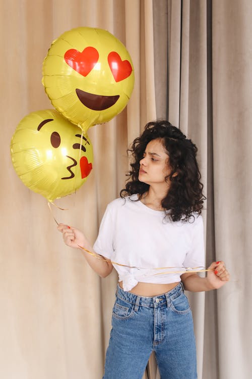 Woman in White Shirt and Blue Denim Shorts Holding Yellow Balloons