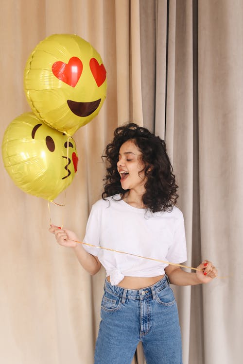 Free Woman in White Shirt and Blue Denim Shorts Holding Yellow Balloons Stock Photo