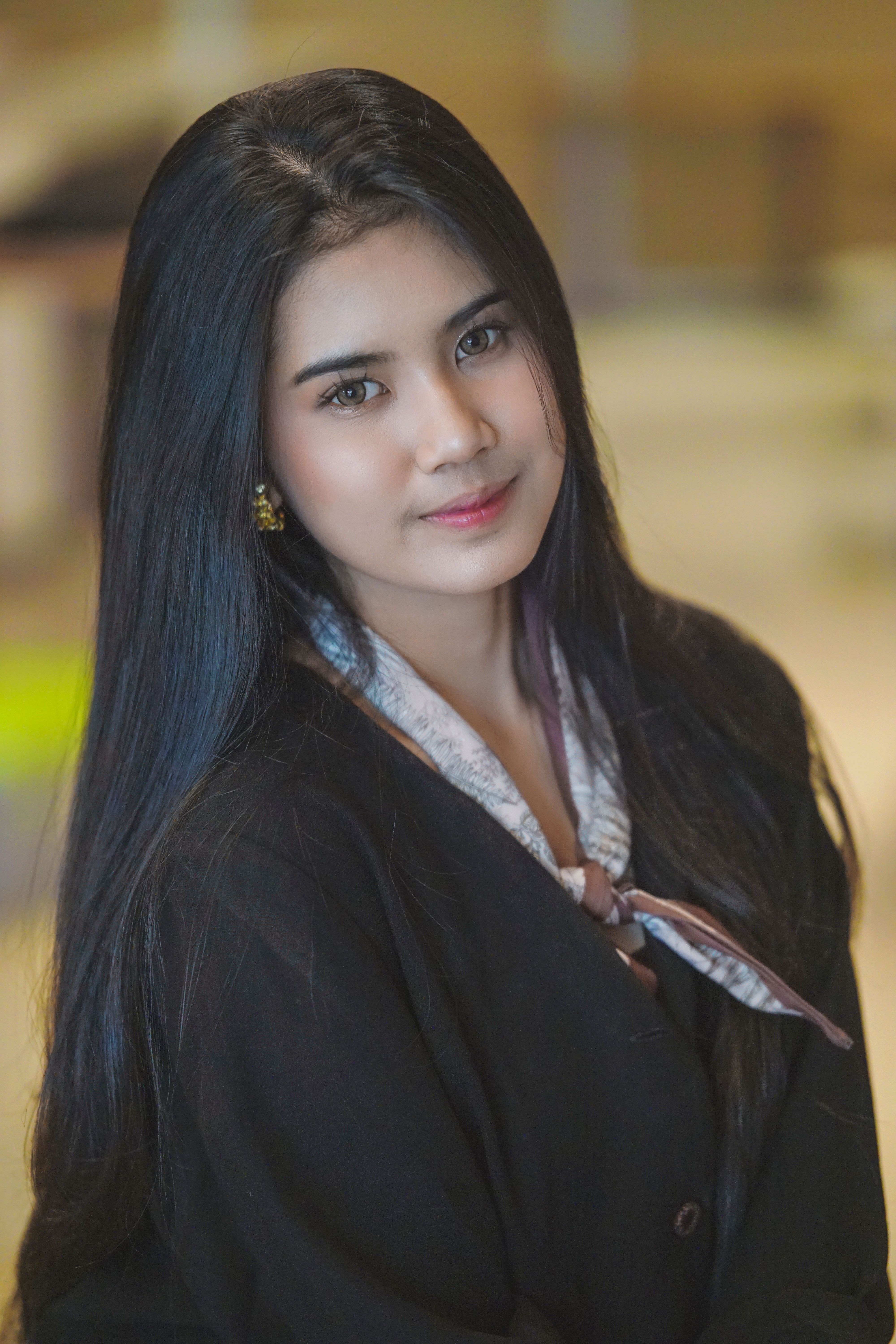 A portrait of a young woman with long dark hair, wearing a black outfit indoors.