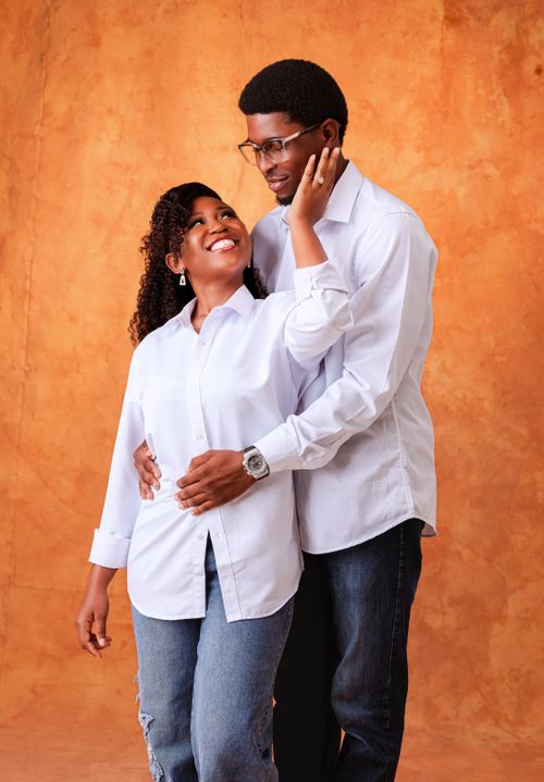 Free Smiling couple in casual attire sharing a joyful moment in a studio setting. Stock Photo