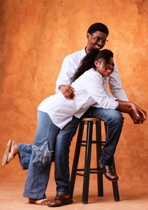 Free Couple in casual wear enjoying a playful moment against a warm backdrop in a studio. Stock Photo