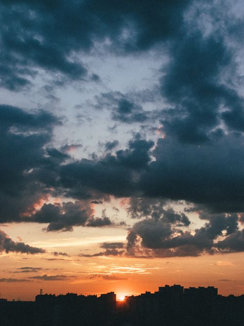 Free A vibrant sunset skyline with dramatic clouds over a cityscape. Stock Photo