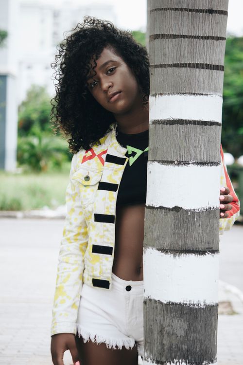 Free Chic fashion portrait of an African woman with curly hair by a tree. Stock Photo