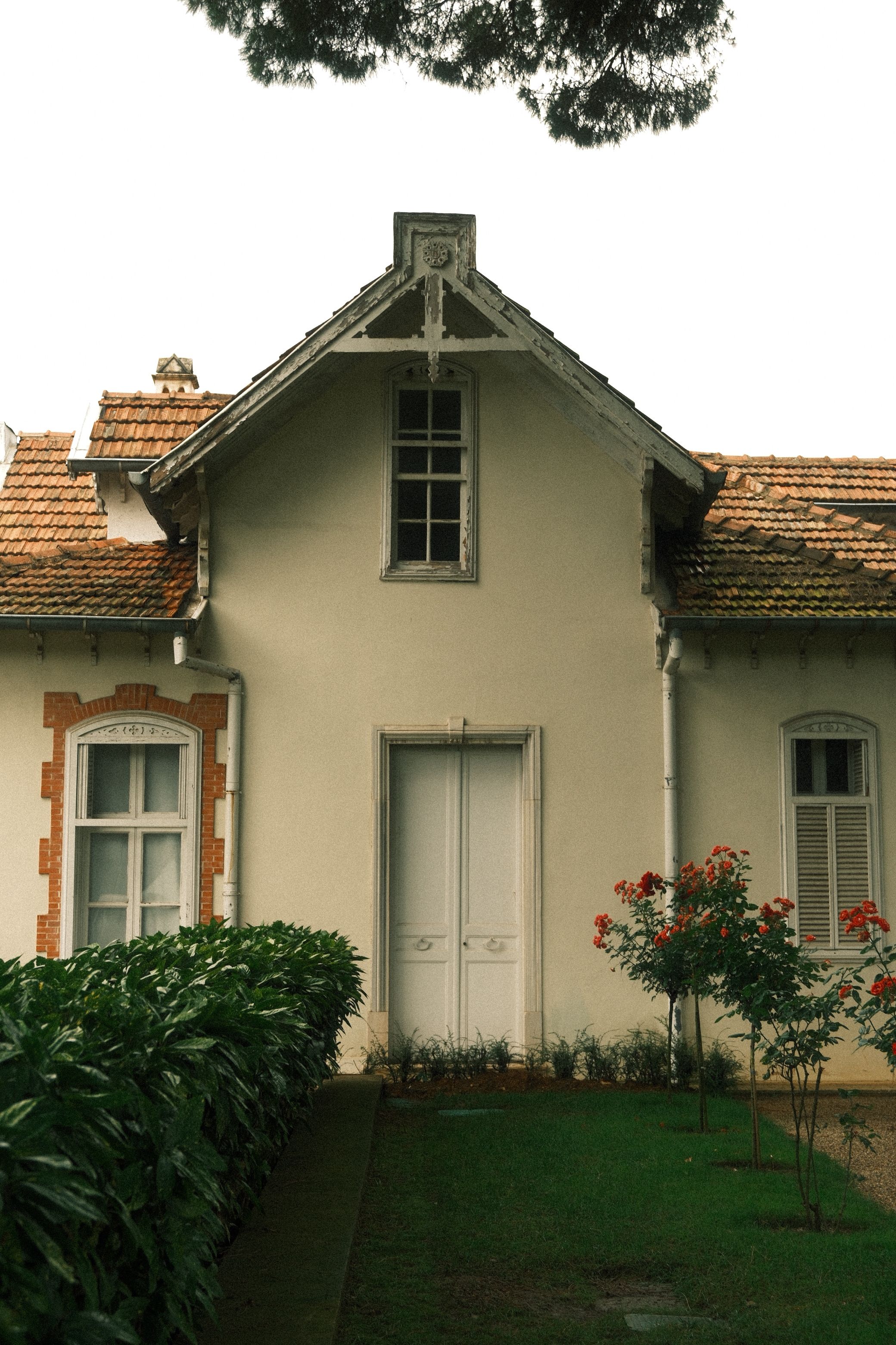 Charming vintage house with a distinctive gable roof and brick detailing surrounded by greenery.