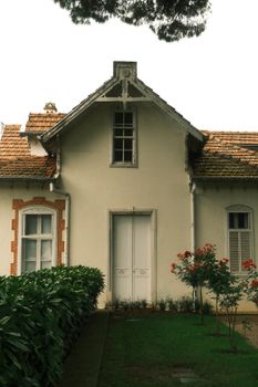 Charming vintage house with a distinctive gable roof and brick detailing surrounded by greenery.