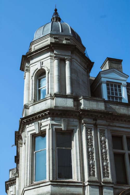 Free Captivating view of classic UK building architecture with a distinctive dome and blue sky backdrop. Stock Photo