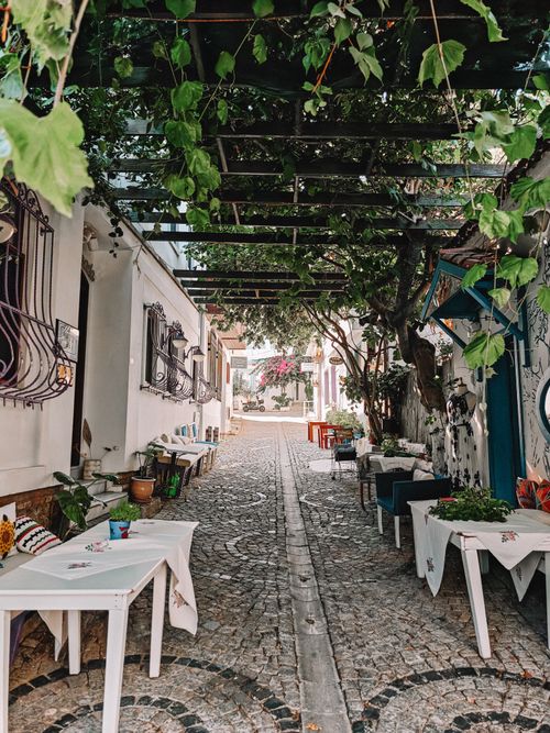 Free Picturesque alley with shaded outdoor seating and vine-covered pergola. Stock Photo