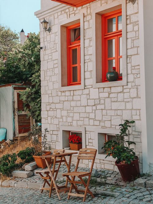 Free Cozy outdoor cafe setting with wooden chairs and rustic stone walls, perfect for a summer day. Stock Photo