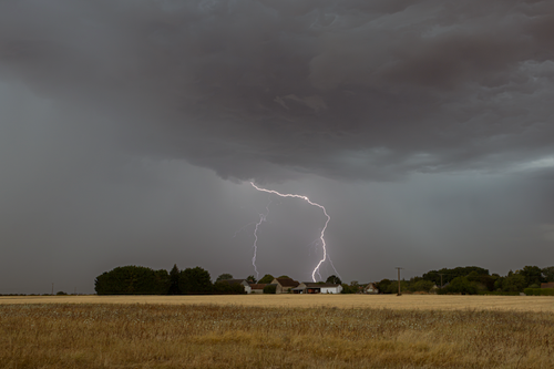 Free Stormy countryside landscape featuring a lightning strike and ominous clouds. Stock Photo