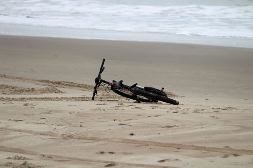 Free A bicycle rests on the sandy shores of Guaratuba beach, Paraná, Brazil, with ocean waves in the background. Stock Photo