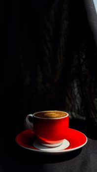 A striking red cup of cappuccino casting artistic shadows, creating a moody ambiance.