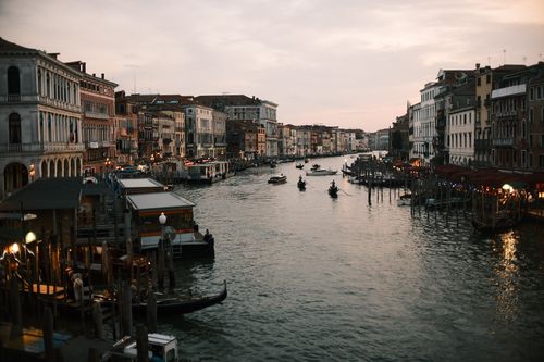 Free Scenic view of Venice's Grand Canal at sunset with gondolas and historic architecture. Stock Photo
