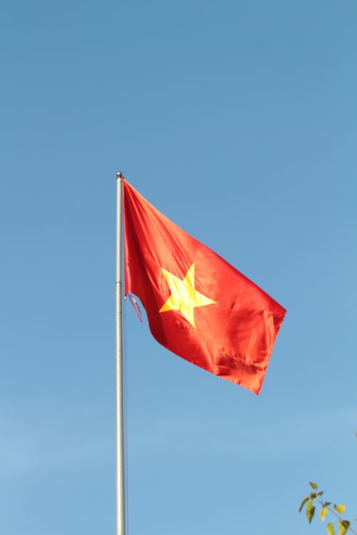 Free Vietnamese national flag waving in the breeze under a clear blue sky, symbolizing national pride and freedom. Stock Photo