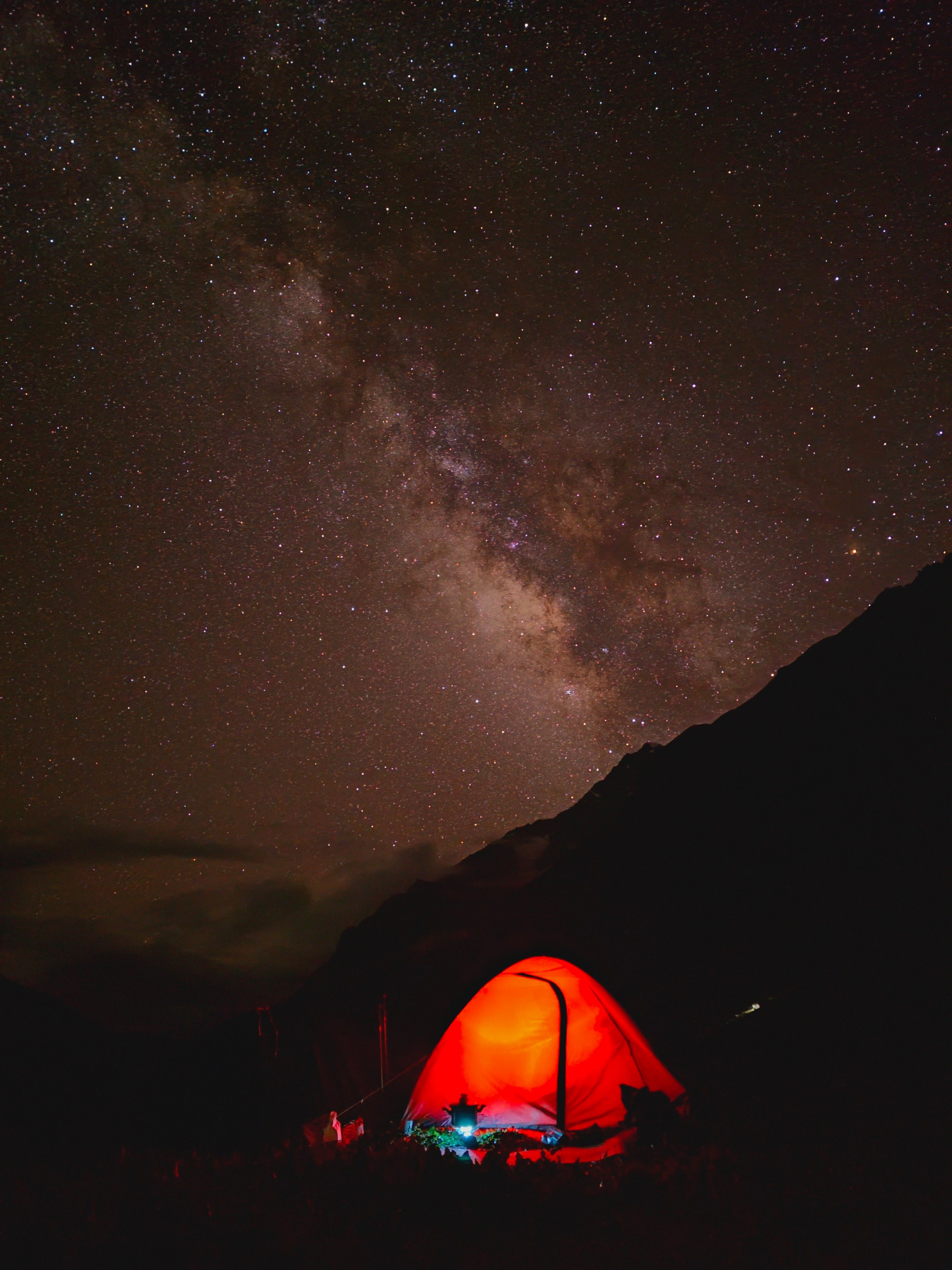 A vibrant red tent beneath a stunning starry sky and the Milky Way in Kishtwar.