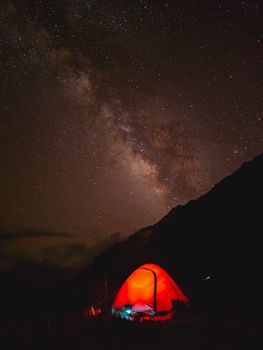 A vibrant red tent beneath a stunning starry sky and the Milky Way in Kishtwar.