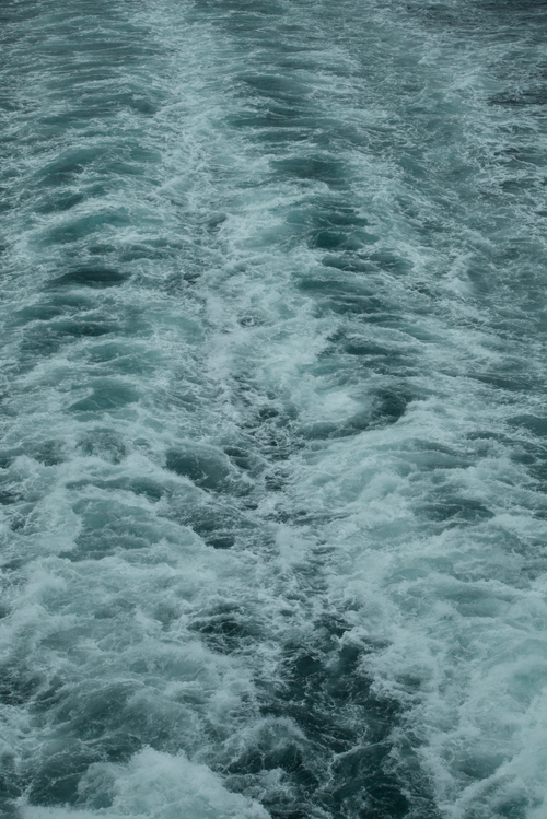 Free Dynamic ocean waves creating patterns behind a moving boat. Stock Photo