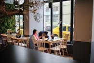 一位女士坐在时尚的餐厅里，这里光线自然，还有绿植和街景