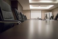 Empty conference room with black chairs, projector, and glasses on table. Ideal for business meetings.