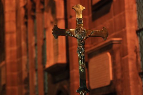 Free A detailed brass crucifix inside a church with warm lighting, creating a spiritual atmosphere. Stock Photo