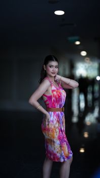Stylish young woman posing confidently in a vibrant tie-dye dress indoors, Jakarta.